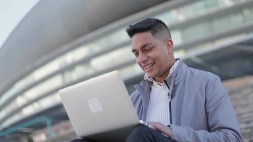 Young Man Using Laptop Celebrating Success Outdoors