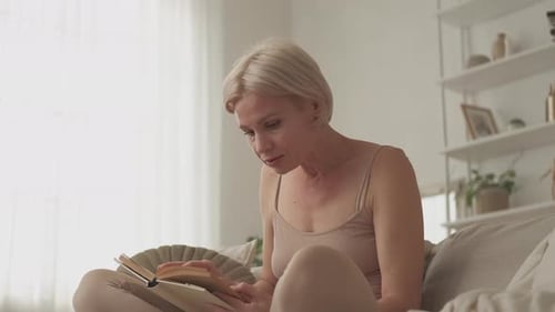 Woman Relaxes Reading a Book on Sofa