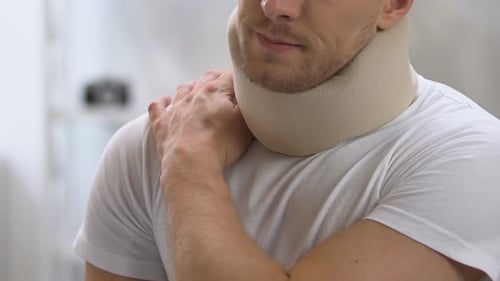 Man wearing cervical collar touching neck
