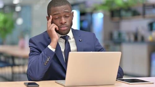 Stressed African Businessman with Laptop Having Headache in Office