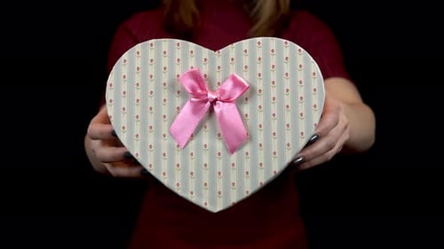 Woman Holds Heart-Shaped Gift Box With Pink Ribbon