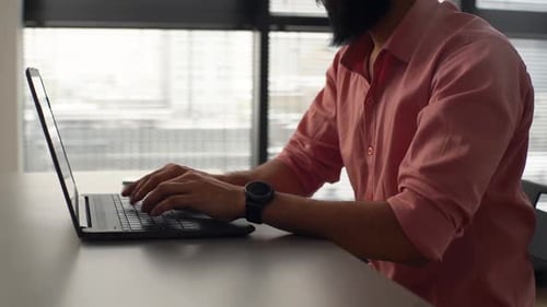 Man Typing on Laptop in Modern Office