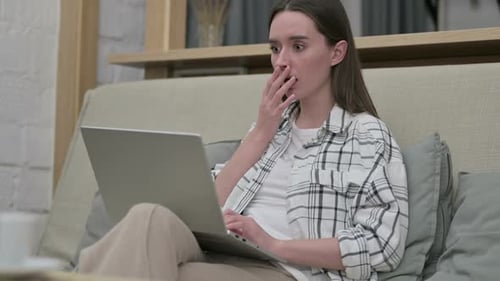 Young Woman Reacting to Failure on Laptop on Sofa