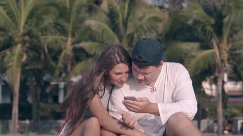 Couple Sharing a Mobile Phone on Tropical Beach
