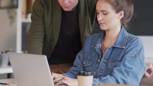Woman Typing on Laptop with Man Observing