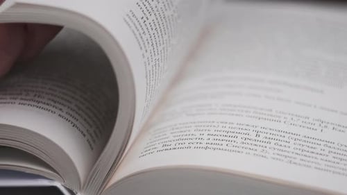 Hand Turns Pages of a Large Book