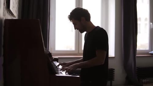 Man Plays the Piano in Dimly Lit Room