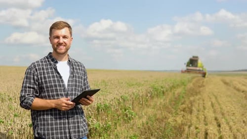 Farmer in Wheat Field Holding Digital Tablet