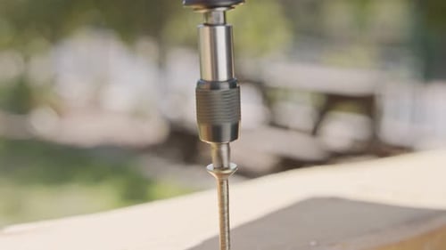 Slow motion of a man using an electric screwdriver to drive a screw into wood