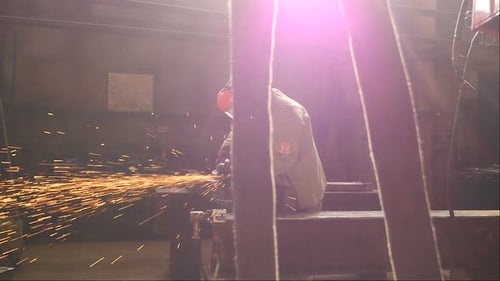 Welder in a Special Uniform Gloves and Mask Works at the Factory