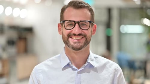 Man Smiles at Camera in Office Setting