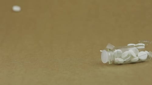Glass Jar Falls and Broke. White Round Pills Fall Out of It. Slow Motion