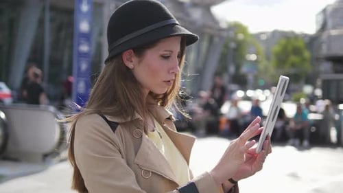 Young Attractive Female in Stylish Fashion Clothes Using Digital Tablet Screen in the City Street