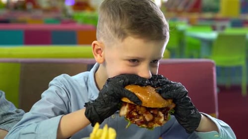 Child Eating a Burger Indoors
