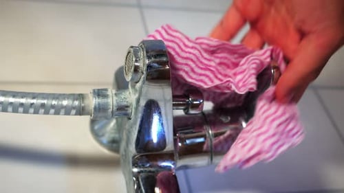 Shiny Faucet Being Cleaned in a Bathroom