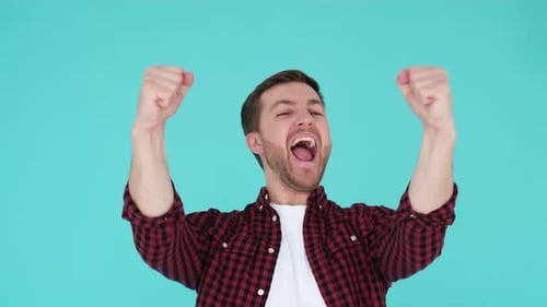 Young Man Cheering with Fists Raised on Blue