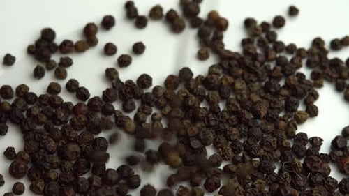 Peppercorns Falling in a Heap on White
