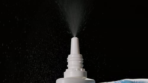 Spraying Liquid From a Vial of Medicine for the Nose on a Black Background. Prevention of COVID 19