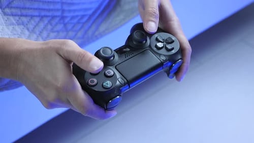 Hands tapping buttons and pushing joystick on video game controller.