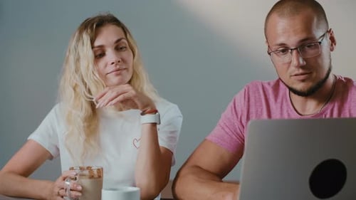 Young couple working together in coffee shop with laptop browsing online.