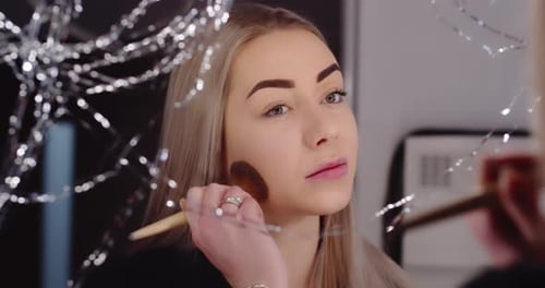 Woman Applying Makeup with Brush in Mirror