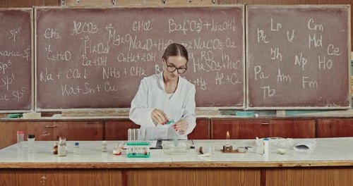 Young Female Technologist or Chemist at Work in a Laboratory Conducting Experiments Adding Chemicals