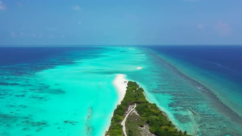 Daytime birds eye island view of a sandy white paradise beach and aqua blue water background