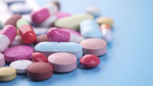 Close Up of Colorful Pills Spilling on Blue Background