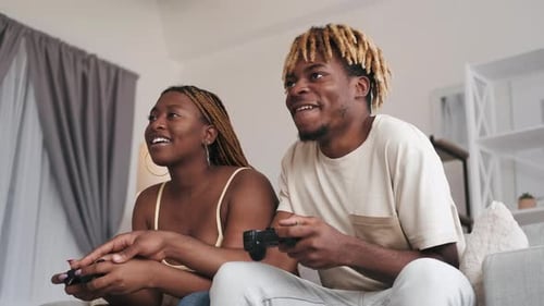 Couple Playing Video Games, Laughing on Sofa