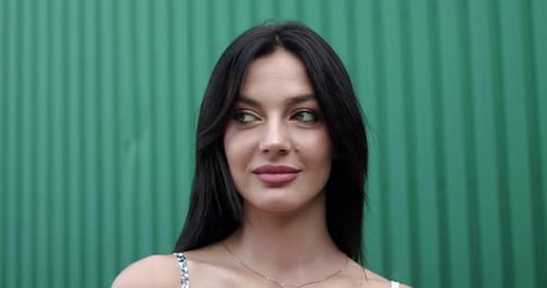 Beautiful Woman Smiling in Front of a Green Wall
