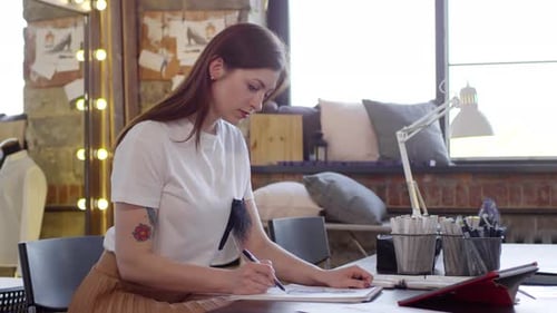 Beautiful Female Designer Drawing Fashion Sketch in Sewing Studio