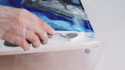 Manchas de resina epoxi blanca en la pintura con una espátula en una pintura abstracta