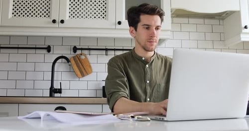 Mann sitzt in der Küche und codiert HTML auf Laptop. IT-Sphäre. Konzept von zu Hause aus arbeiten