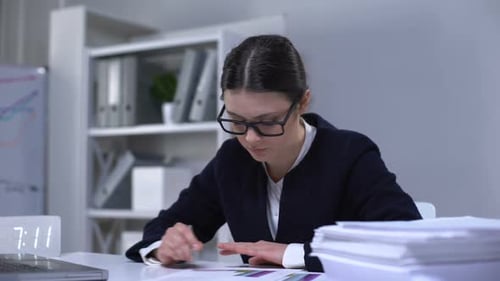 Zufriedene Buchhalterin, die Dokumente durchschaut und sich glücklich mit der Arbeit fühlt