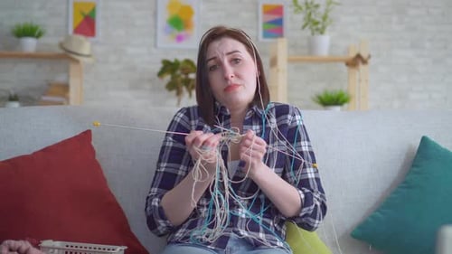Woman Knitting with Yarn at Home on Couch