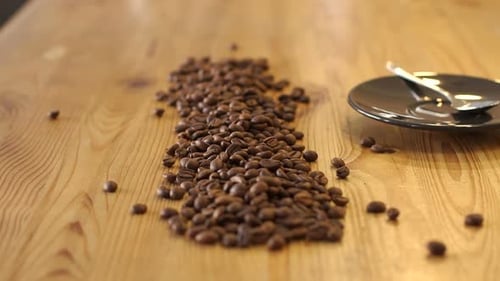 Barista Pours Out Coffee Beans From a Bag on a Wooden Table in a Coffee Shop