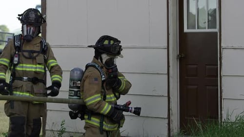 Firefighters Standing at Ready Outside House