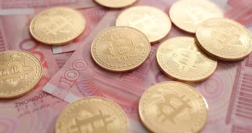 Gold Bitcoins on Chinese Yuan Banknotes Close Up
