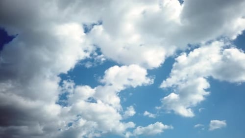 Fluffy White Clouds Drifting Across Blue Sky