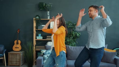 Happy Young Couple Dancing in their Living Room