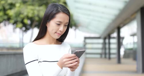 Mujer jugando un juego de Aplicación teléfonos móviles al aire libre