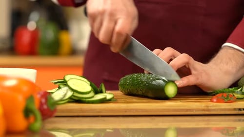 Chef chopping fresh, green cucumber.