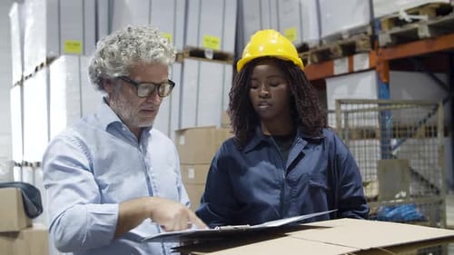 Focused Caucasian Boss and Female Worker Talking in Warehouse