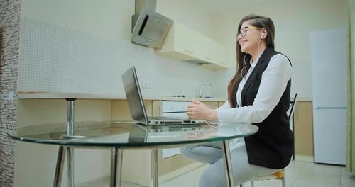 Woman Using Laptop in Kitchen at Table