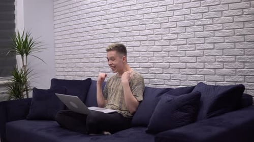 Young Adult Celebrating Success Using Laptop At Home