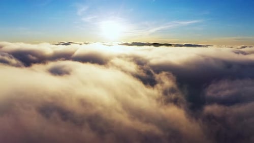 Sun Shining Brightly Above White Fluffy Clouds at Sunrise