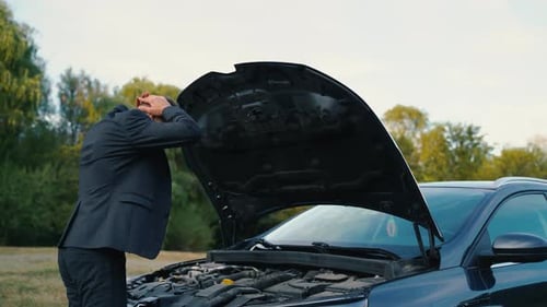 Rückansicht eines Mannes untersucht kaputtes Auto im Freien