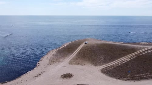 Un avion suit une voiture qui se déplace dans la steppe le long de la mer contre le ciel bleu
