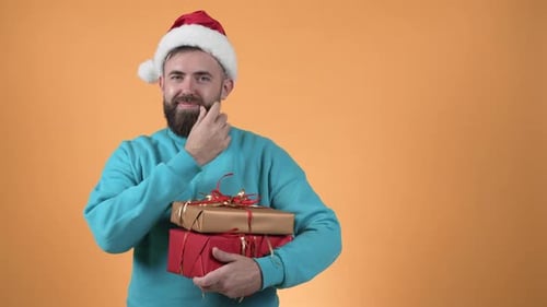 Man in Santa Hat Holds Christmas Gifts