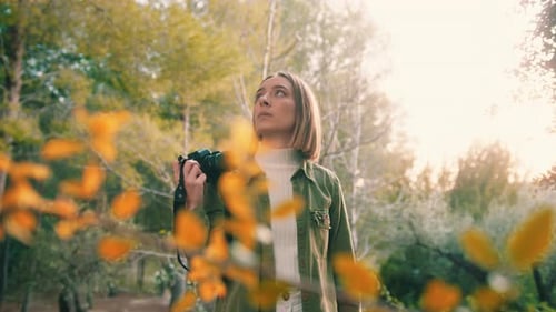 Woman with Camera Looks Upward in Green Nature
